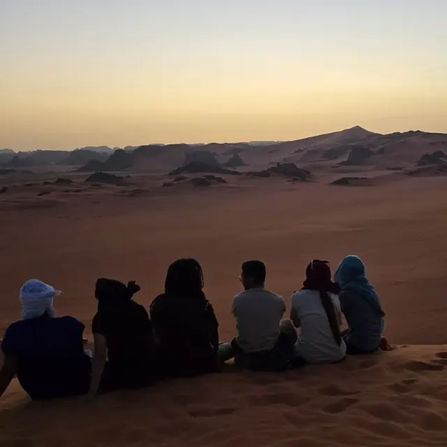 Voyageurs assis sur une dune, contemplant le désert au crépuscule