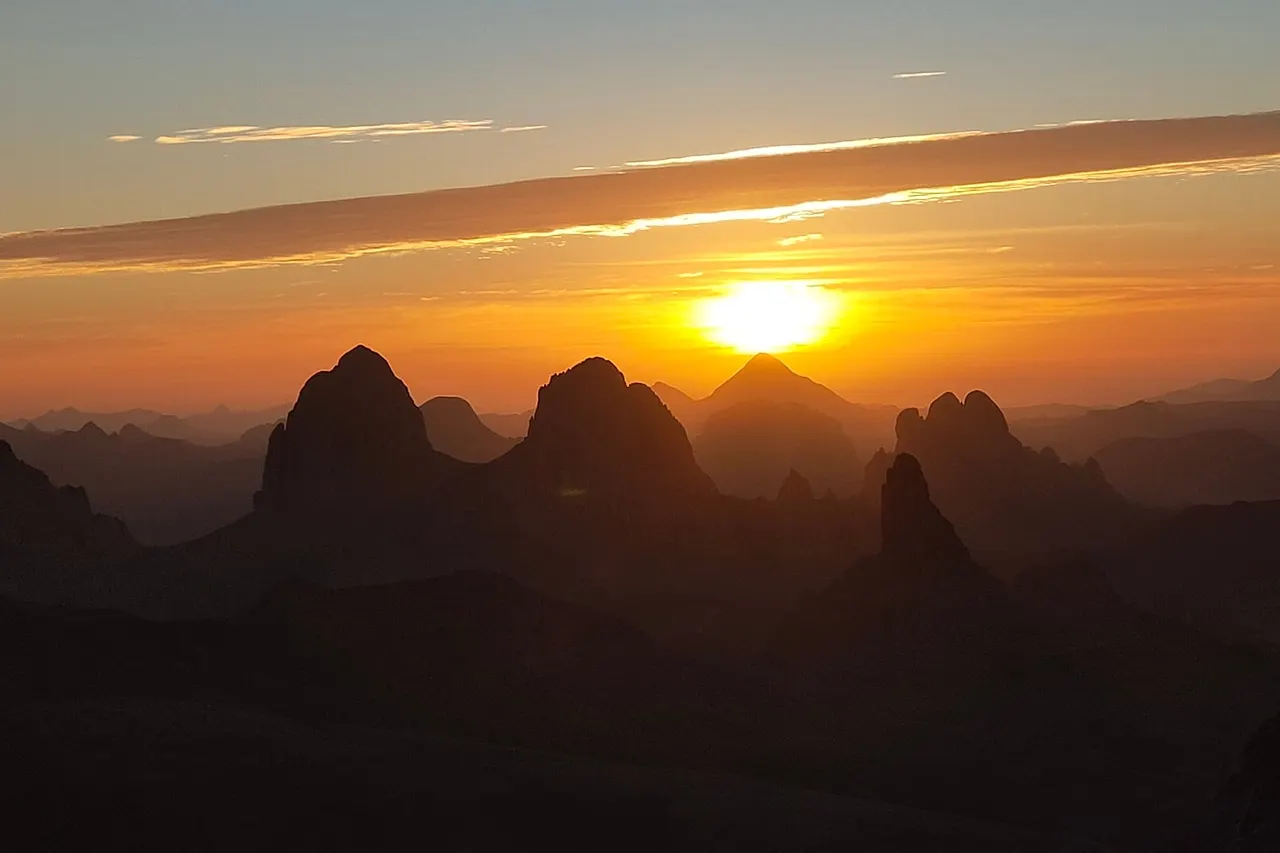 Lever du soleil derrière les pics volcaniques, vu depuis le plateau de l'Assekrem