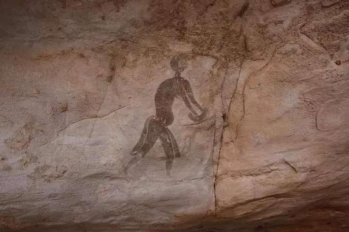 Peinture rupestre d'un personnage en mouvement sur une paroi de grès